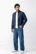 A man modeling a dark navy blue zip-up linen jacket over a white t-shirt and blue jeans, standing against a plain white studio background.