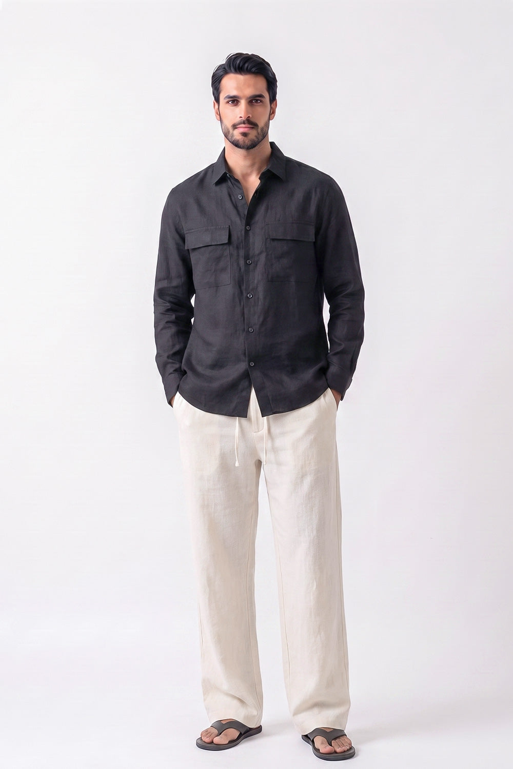 A man modeling a black long-sleeve button-up shirt and off-white hemptrousers against a plain white studio background.
