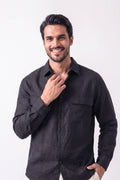 A smiling man wearing a black long-sleeve hemp button-up shirt, posing against a solid white studio background.