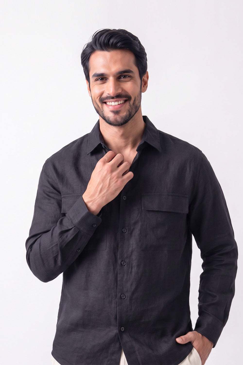 A smiling man wearing a black long-sleeve hemp button-up shirt, posing against a solid white studio background.