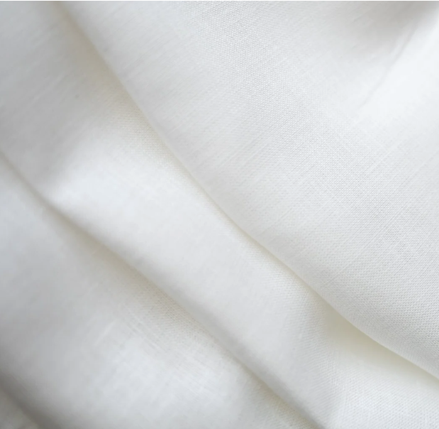 A close-up of draped white fabric with soft folds and a subtle woven texture.