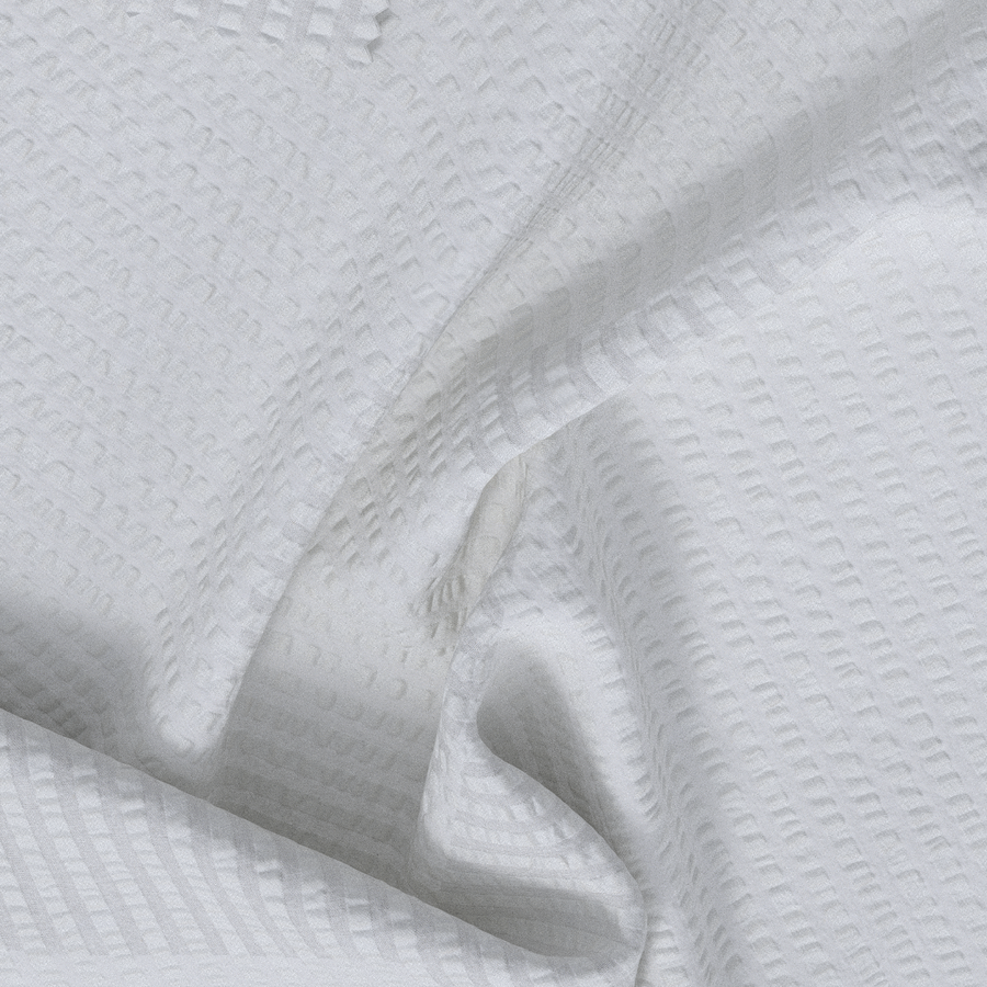A close-up of white textured fabric with a subtle basketweave or waffle-like pattern, shown in soft folds.