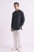 A man modeling a black long-sleeve linen kurta with a mandarin collar and white linen trousers, standing against a light gray studio background.