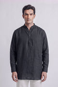 A man wearing a dark charcoal gray linen long-sleeve kurta with a mandarin collar and partial button placket, paired with off-white trousers, standing against a light gray studio background.