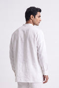 A man shown from the back wearing a white long-sleeve linen shirt and matching white trousers, photographed against a clean white studio background.