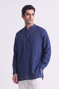 A man wearing a navy blue long-sleeve linen kurta with a mandarin collar and three-button placket, paired with white trousers, photographed against a plain white studio background.