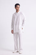 A man modeling a white long-sleeve linen kurta with a split collar and matching white trousers, standing against a plain white studio background.
