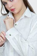 Woman wearing a white shirt with green buttons on a plain background