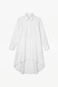 A clean product flat-lay shot of a white long-sleeve linen shirt dress featuring a classic shirt collar, full front button placket, buttoned cuffs, and a curved high-low hemline against a plain white background.