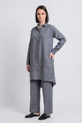 A woman modeling a long-sleeved gray button-up tunic linen  top with matching wide-leg trousers, photographed against a neutral light gray studio background.