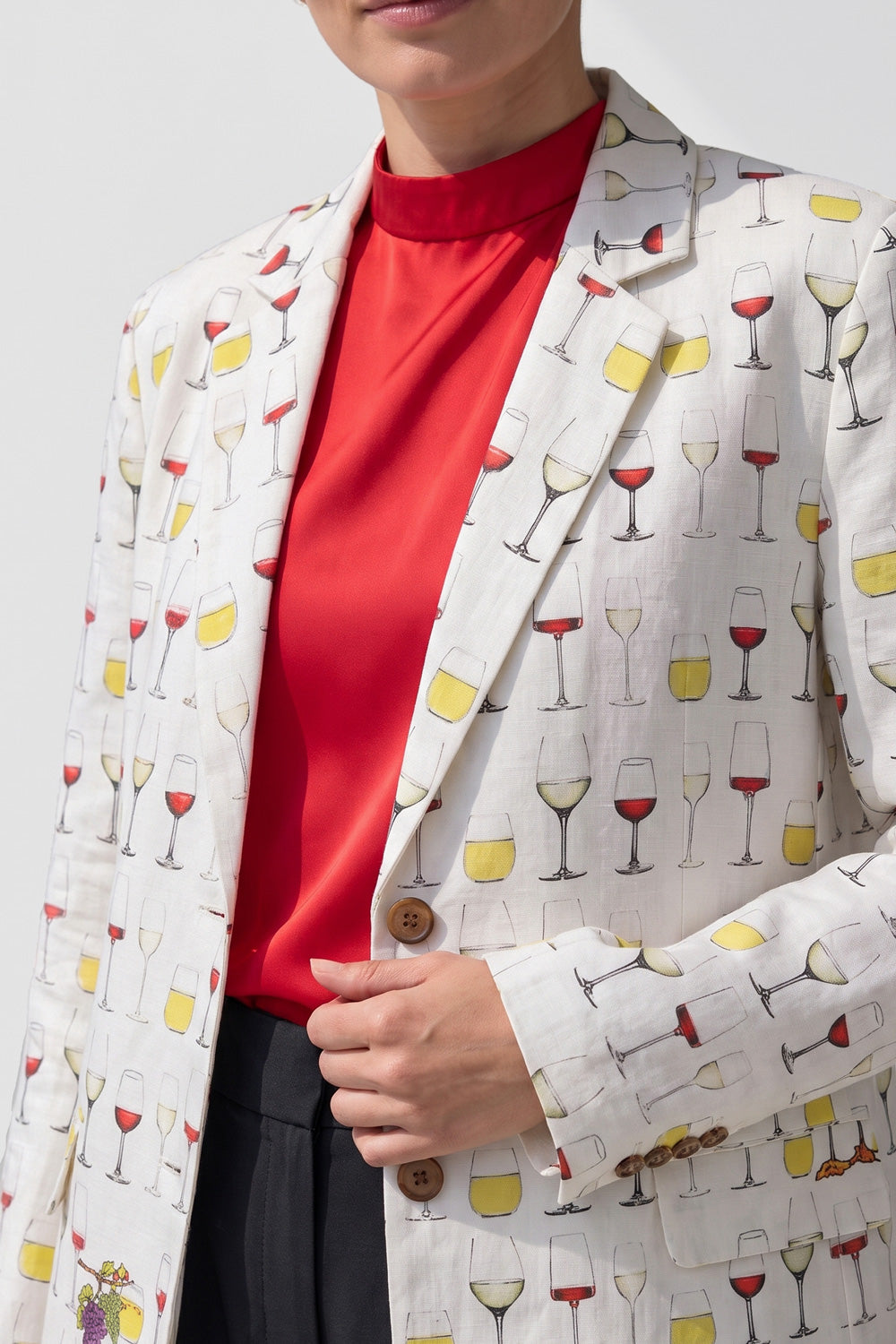 Model wearing the Jam women's hemp boyfriend blazer in offwhite with a wine glass and fox print, over a red top and charcoal wide-leg trousers