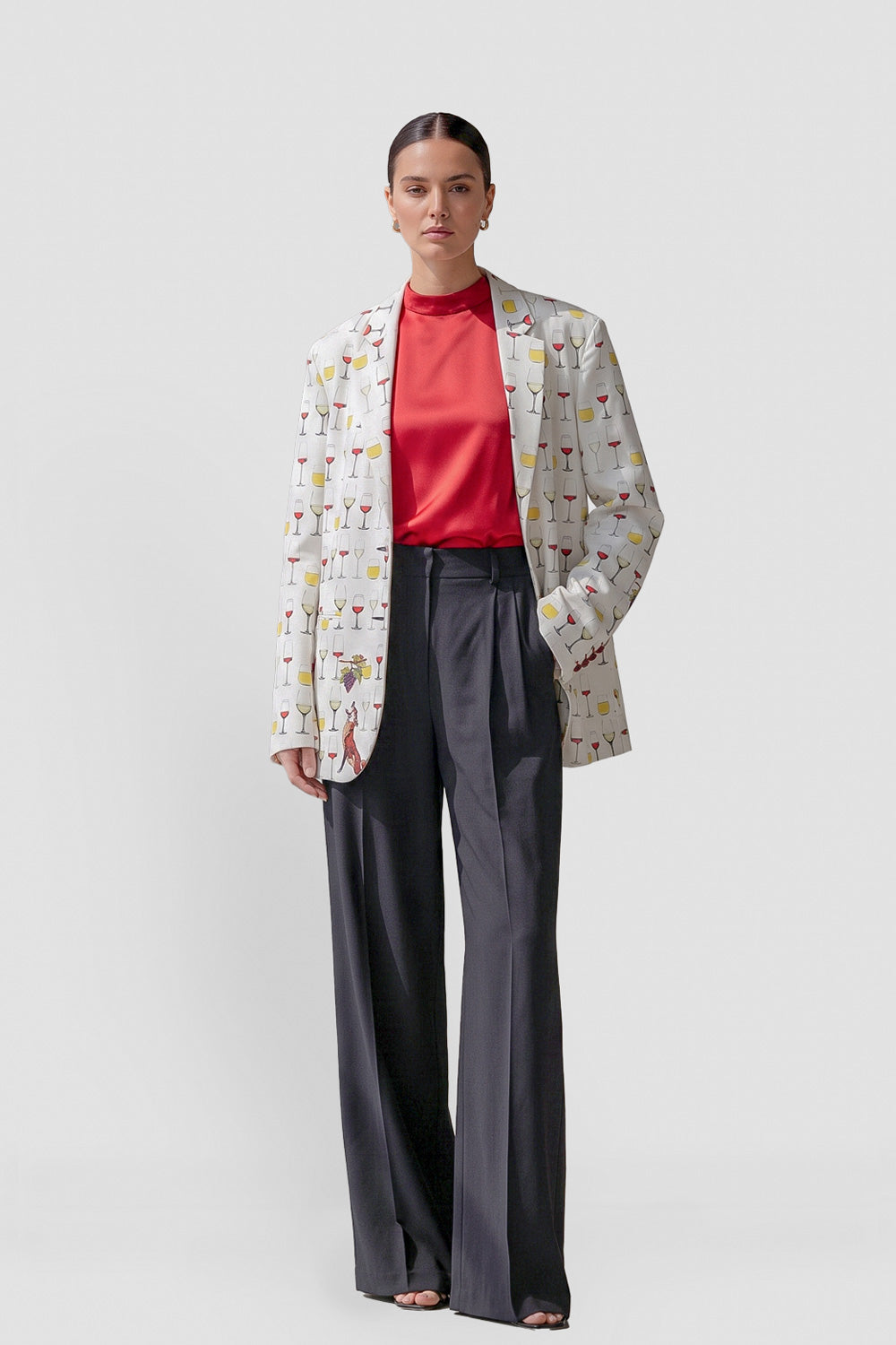 Model wearing the Jam women's hemp boyfriend blazer in offwhite with a wine glass and fox print, over a red top and charcoal wide-leg trousers