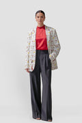 Model wearing the Jam women's hemp boyfriend blazer in offwhite with a wine glass and fox print, over a red top and charcoal wide-leg trousers