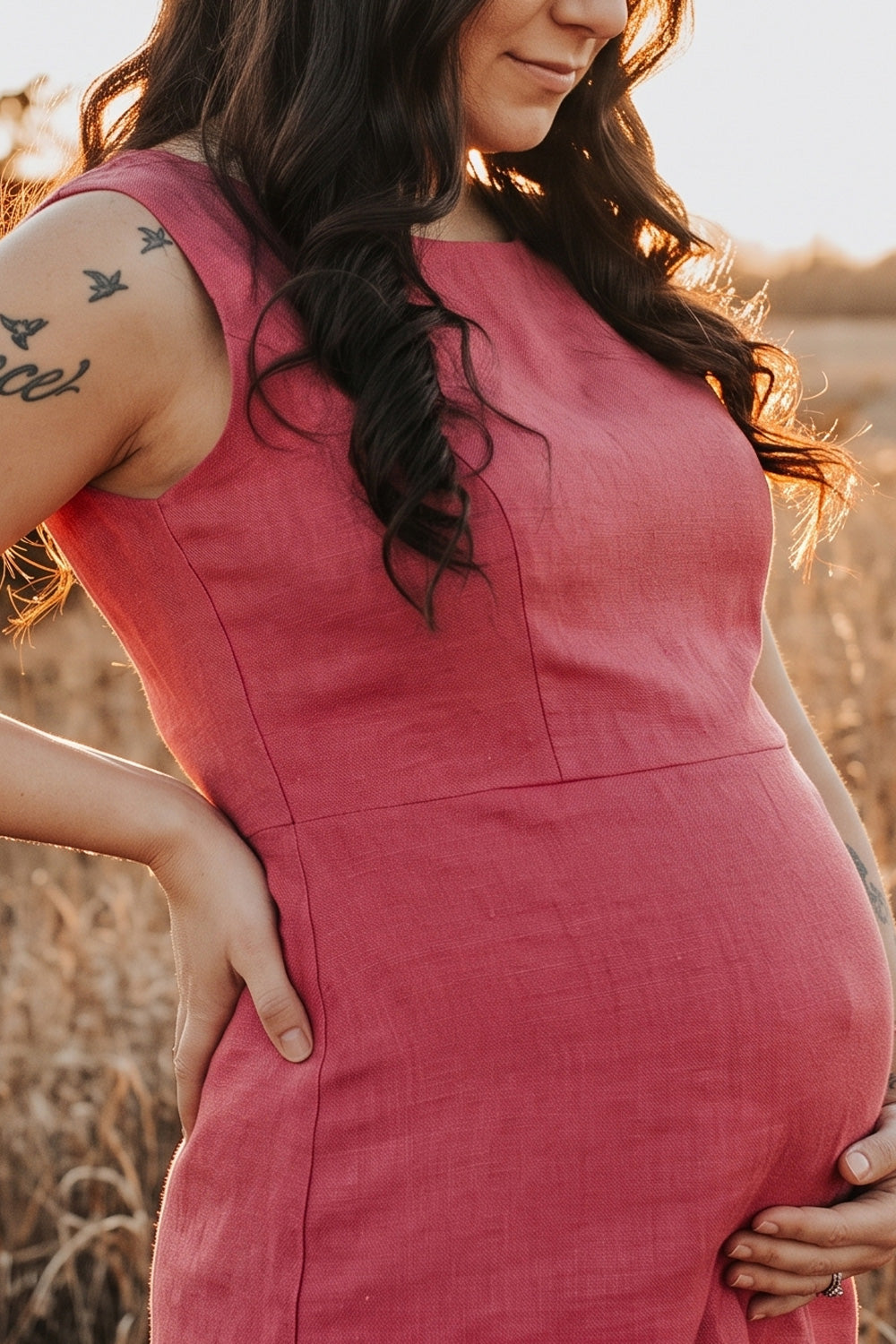A woman modeling a sleeveless, knee-length dusty rose pink linen dress with structured shoulders, standing against a plain white studio background.