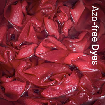 A close-up of glossy, folded red fabric or dye material filling the frame, with vertical white text reading 'Azo-free Dyes' along the right side.