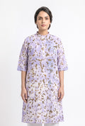 A model wearing a lavender cotton eco-print kurta featuring natural marigold leaf motifs in earthy golden tones. The straight-fit kurta has a mandarin collar, three-quarter sleeves, a short button placket, and side pockets. She is standing against clean white background.