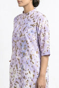 A woman wearing a lavender and white printed kurta with gold foil leopard spots, shown from the side against a plain white background.