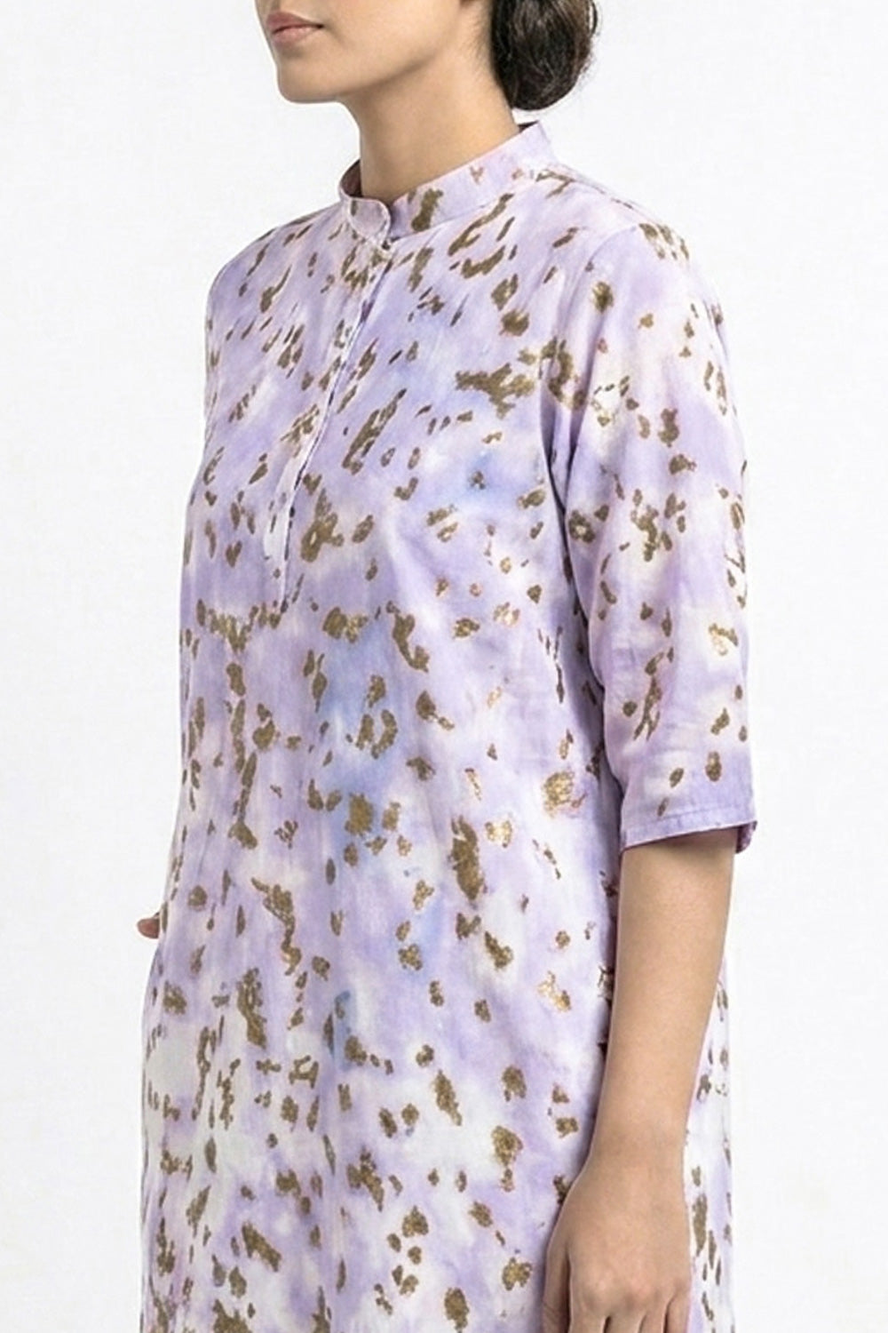 A woman wearing a lavender and white printed kurta with gold foil leopard spots, shown from the side against a plain white background.