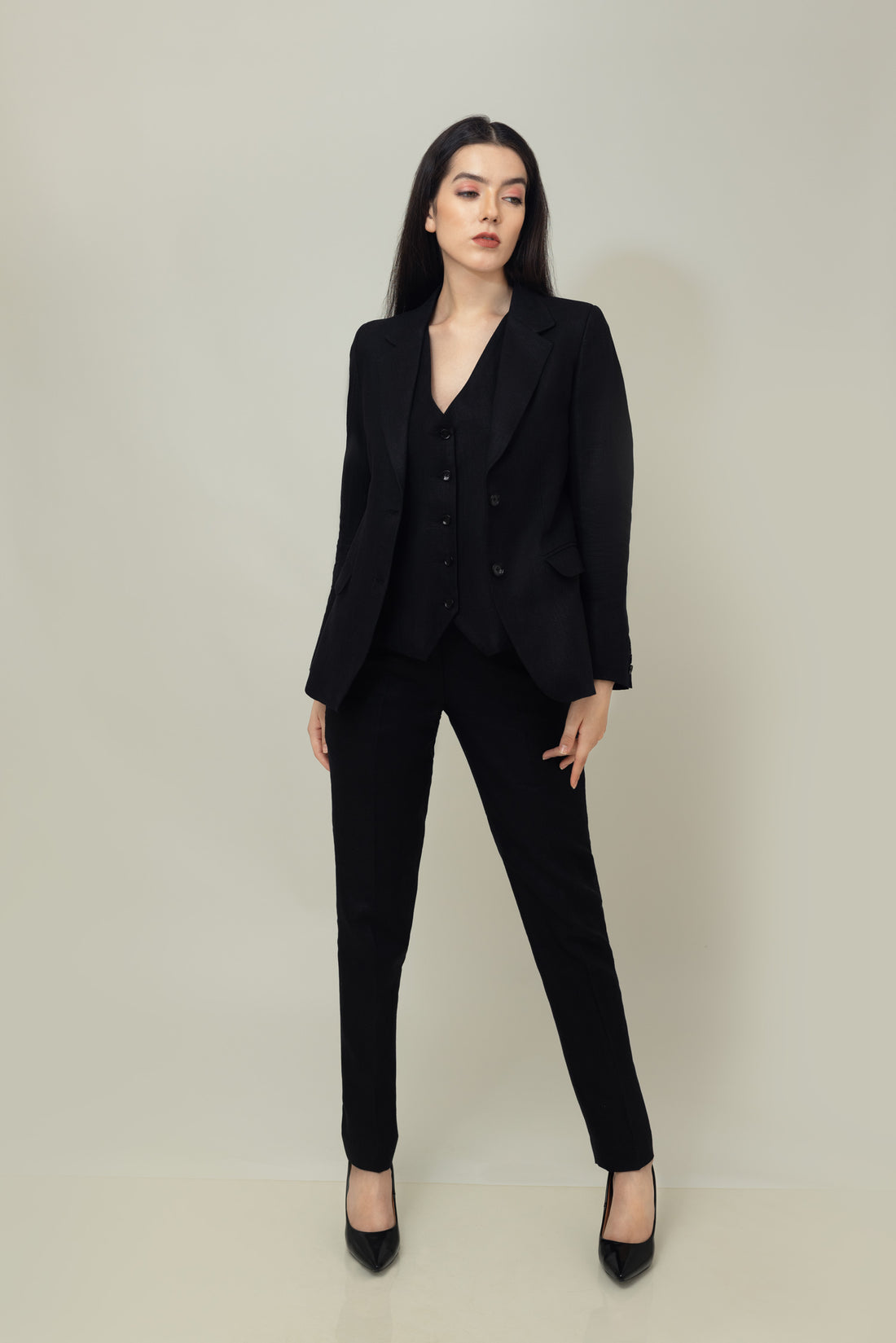 A woman modeling a black linen blazer with a notch lapel, two-button single-breasted design, and flap pockets.