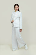 A woman modeling a white linen blazer with a notch lapel, two-button single-breasted design, and flap pockets.