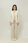 A woman modeling a beige linen blazer with a notch lapel, two-button single-breasted design, and flap pockets.