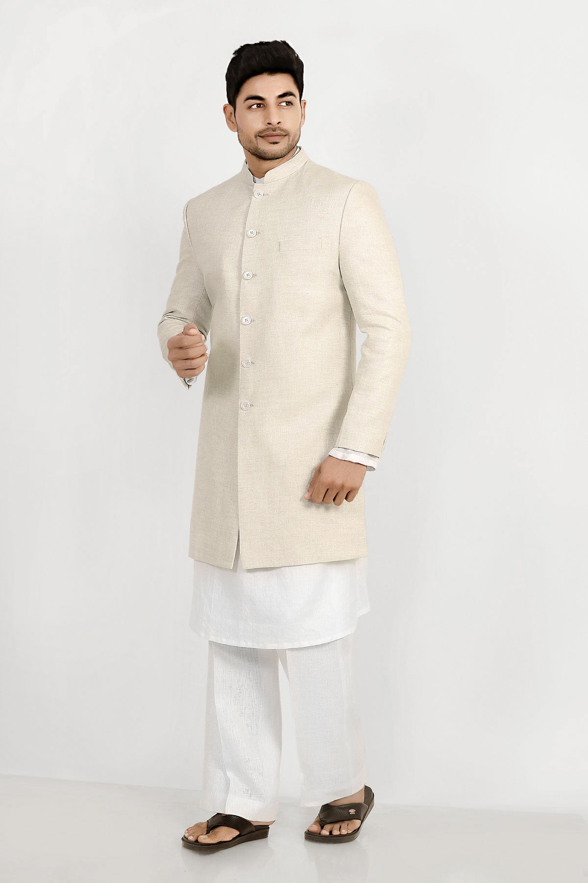 A male model wearing a grey Elm men's linen long coat with a mandarin collar, long sleeves, and front button closures. The coat is fully lined and has a straight fit.