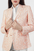Person wearing a peach blazer with a white pattern on a white background