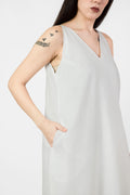 Woman wearing a light gray sleeveless dress against a white background