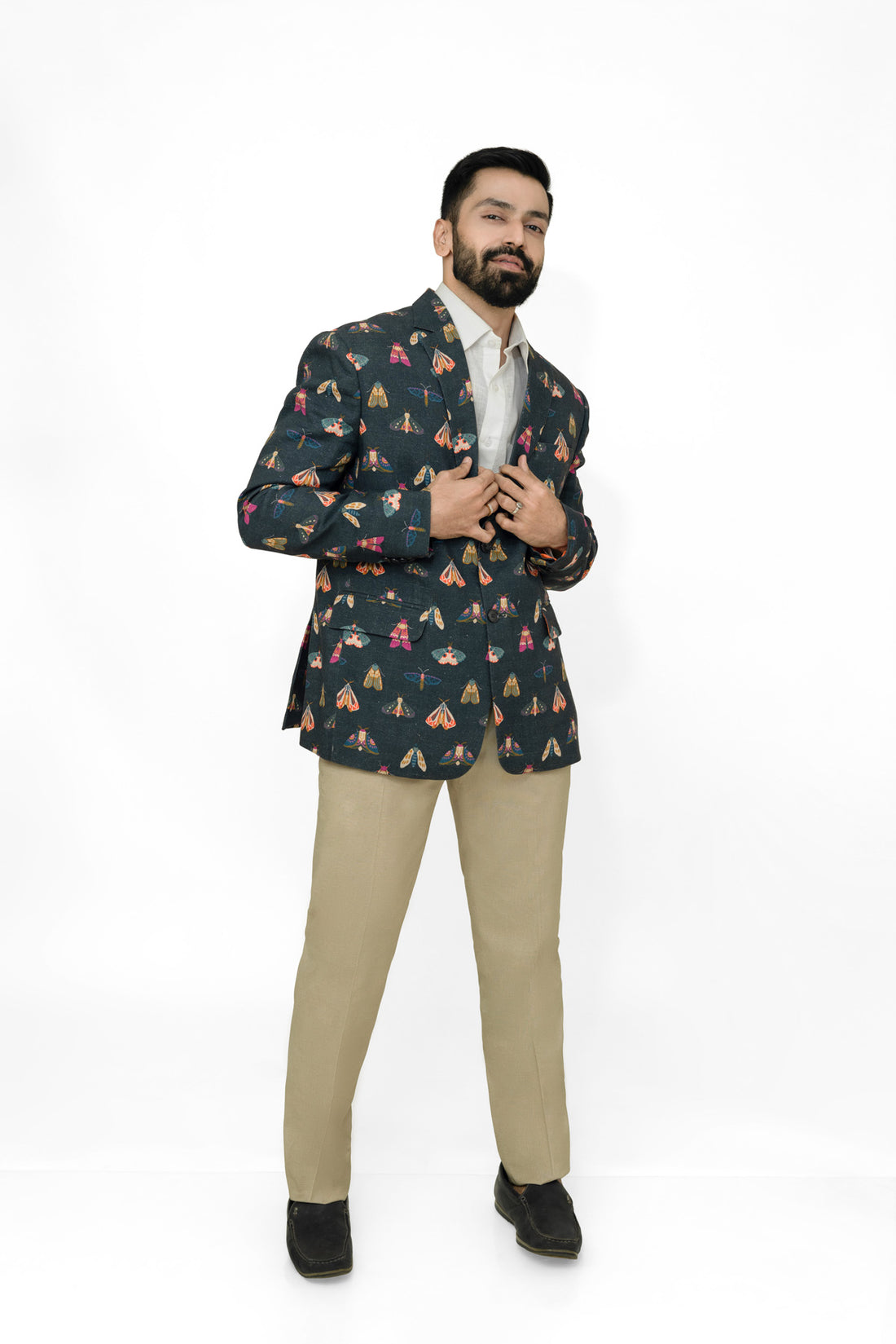 Man wearing a patterned blazer and beige pants on a white background