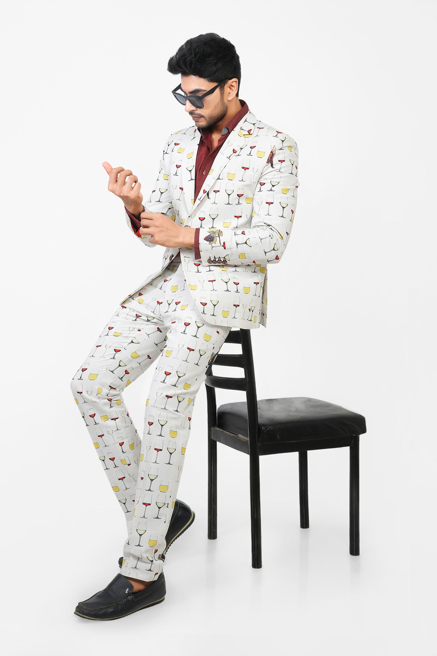 Man wearing a patterned suit sitting on a chair against a white background
