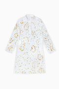 A white long-sleeve tunic dress with a mandarin collar and a scattered abstract gold and green pattern, shown flat against a white background.