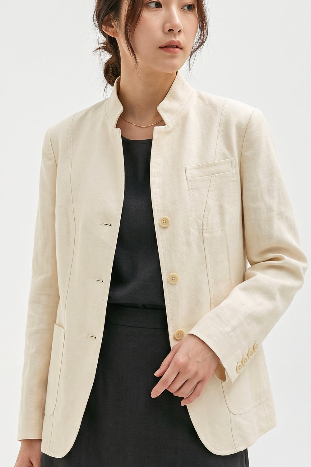 Close-up of the Assam Muga silk jacket showing the mandarin collar, corozo buttons, chest pocket and panel stitching