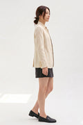 Side view of a model in the Assam Muga silk jacket with a black mini skirt and loafers