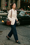 Woman walking in the Assam Muga silk jacket with dark wide-leg jeans and loafers