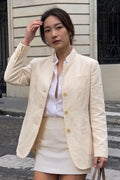 Woman wearing the Assam Muga silk jacket open over a white shirt with a cream mini skirt