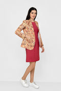A woman modeling a beige and orange floral print linen blazer over a solid red dress, paired with white sneakers, against a plain white studio background.
