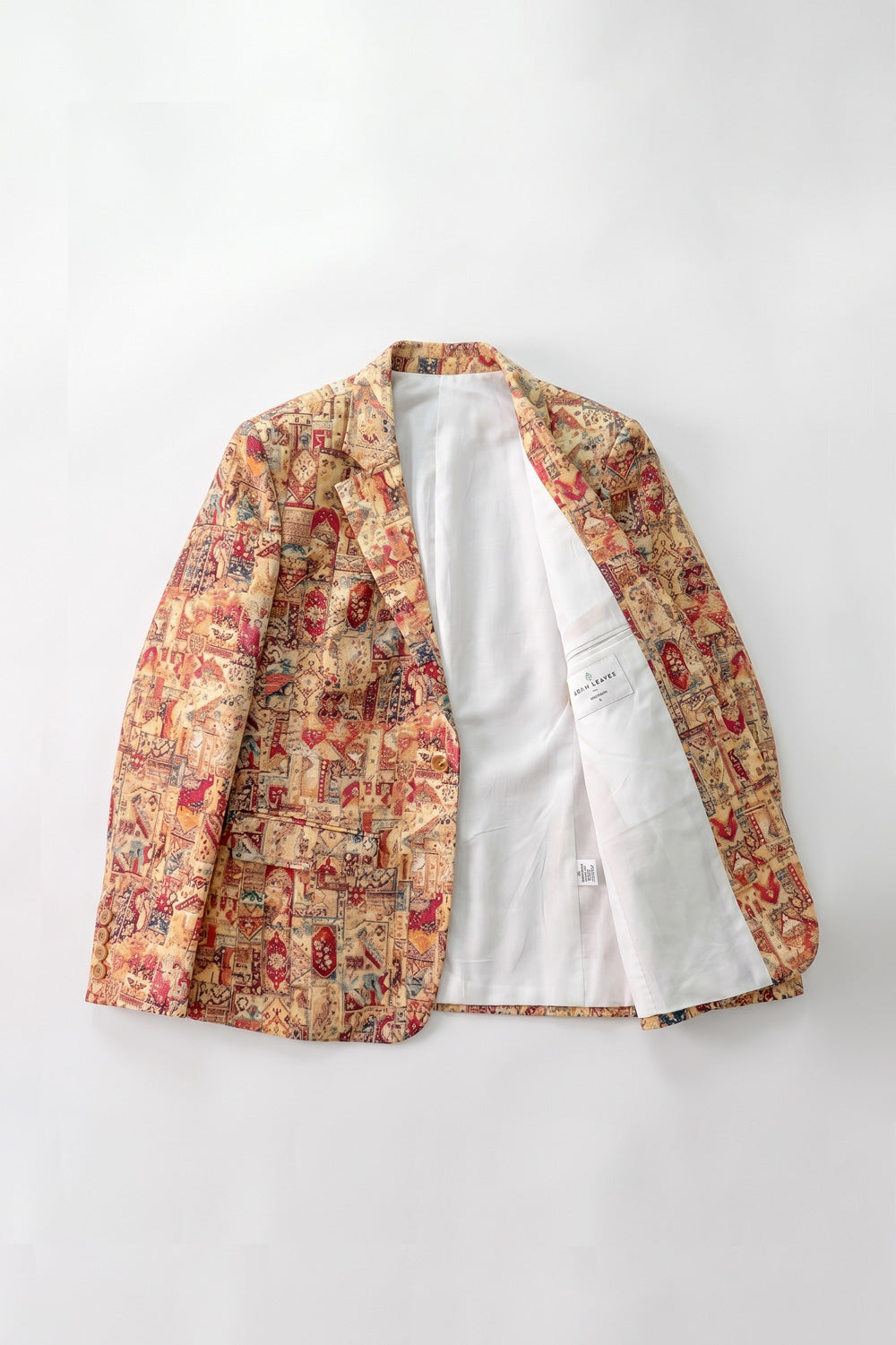 A men's open-front linen blazer jacket featuring a busy, multicolor patchwork print on the exterior and a solid white interior lining, laid flat against a light gray background.