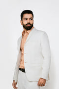 A male model wearing a white hemp blazer with a notch lapel, three buttons, two flap pockets and a chest pocket. The blazer is fully lined with a cotton satin interior.