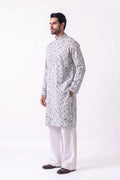 A man modeling a light gray long-sleeve hemp kurta with a subtle circular pattern, paired with white trousers and dark brown shoes, standing against a plain white studio background.