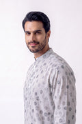 A man wearing a light gray long-sleeve hemp kurta with a dark gray polka dot pattern, photographed against a plain white studio background.