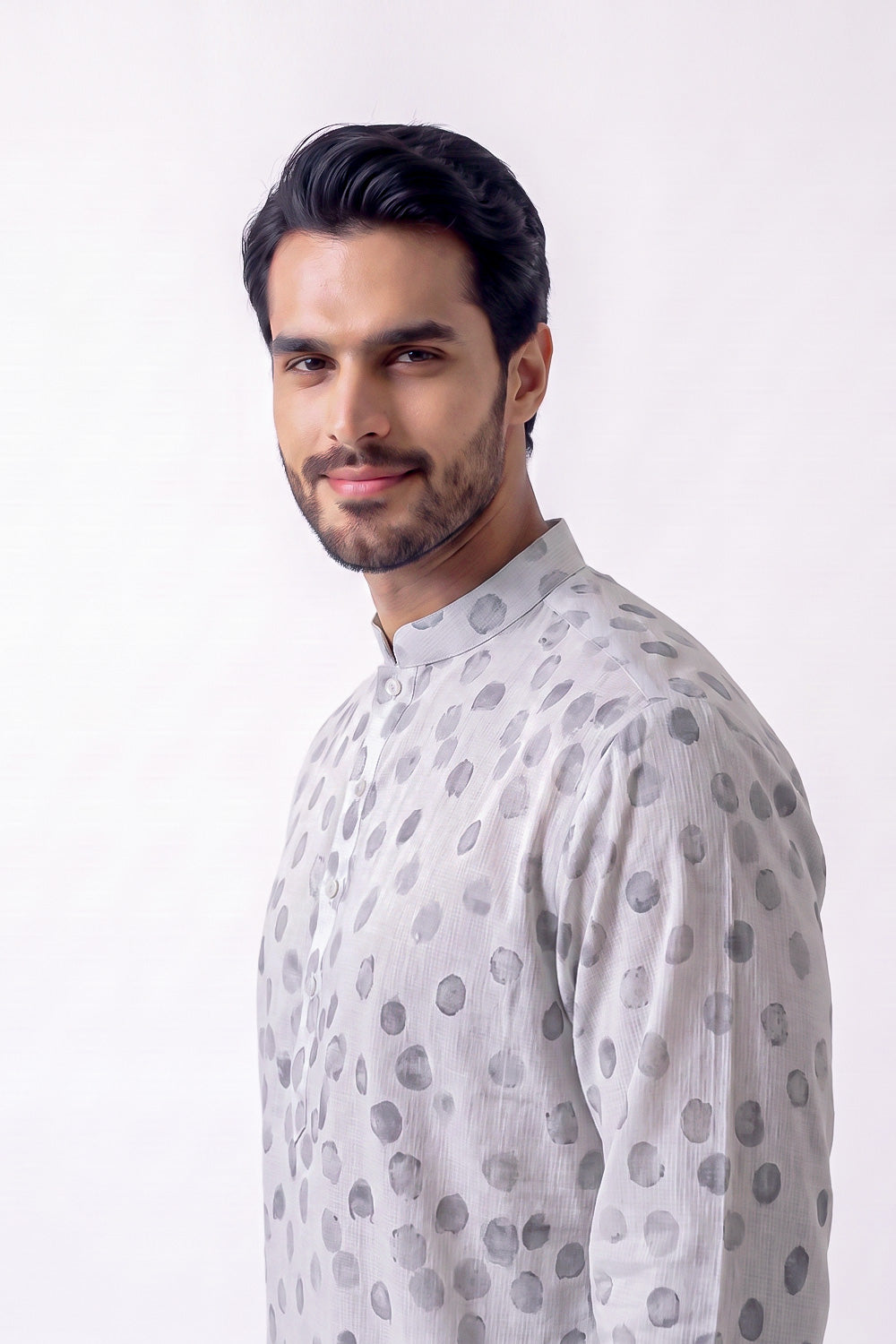 A man wearing a light gray long-sleeve hemp kurta with a dark gray polka dot pattern, photographed against a plain white studio background.