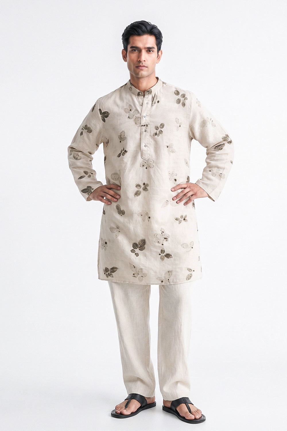 A man modeling a light beige kurta with a dark brown floral print and matching beige trousers, standing against a plain white studio background.