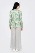 Woman wearing a patterned jacket and light gray pants on a white background