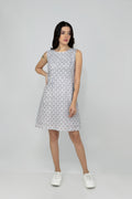 A woman models a mid-length sleeveless linen dress with a geometric pattern, featuring a boat neck and rear zip opening.