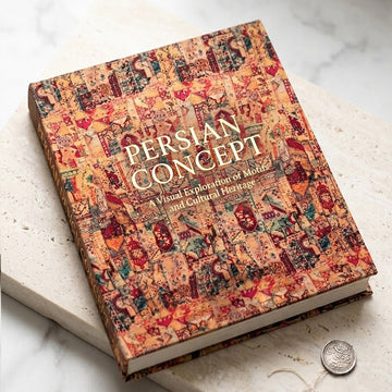 A hardcover book titled 'PERSIAN CONCEPT: A Visual Exploration of Motif and Cultural Heritage' lies diagonally on a light marble surface. The cover is decorated with a dense, intricate collage of traditional Persian miniature illustrations in warm tones of orange, beige, red, and brown.