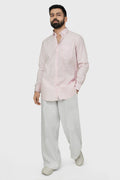 Man wearing a light pink shirt and beige pants on a white background