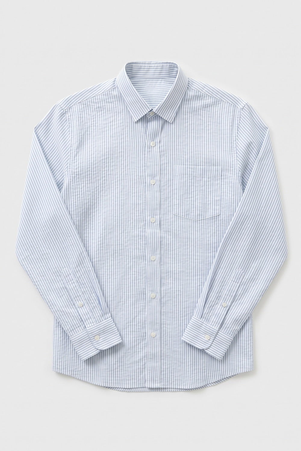 A long-sleeve button-up linen shirt with a fine blue and white vertical stripe pattern, featuring a classic collar, chest pocket, and buttoned cuffs, laid flat against a light gray background.