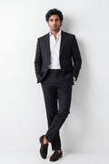 A man wearing a black two-piece hemp suit with a white dress shirt and dark brown loafers, standing against a plain white studio background.