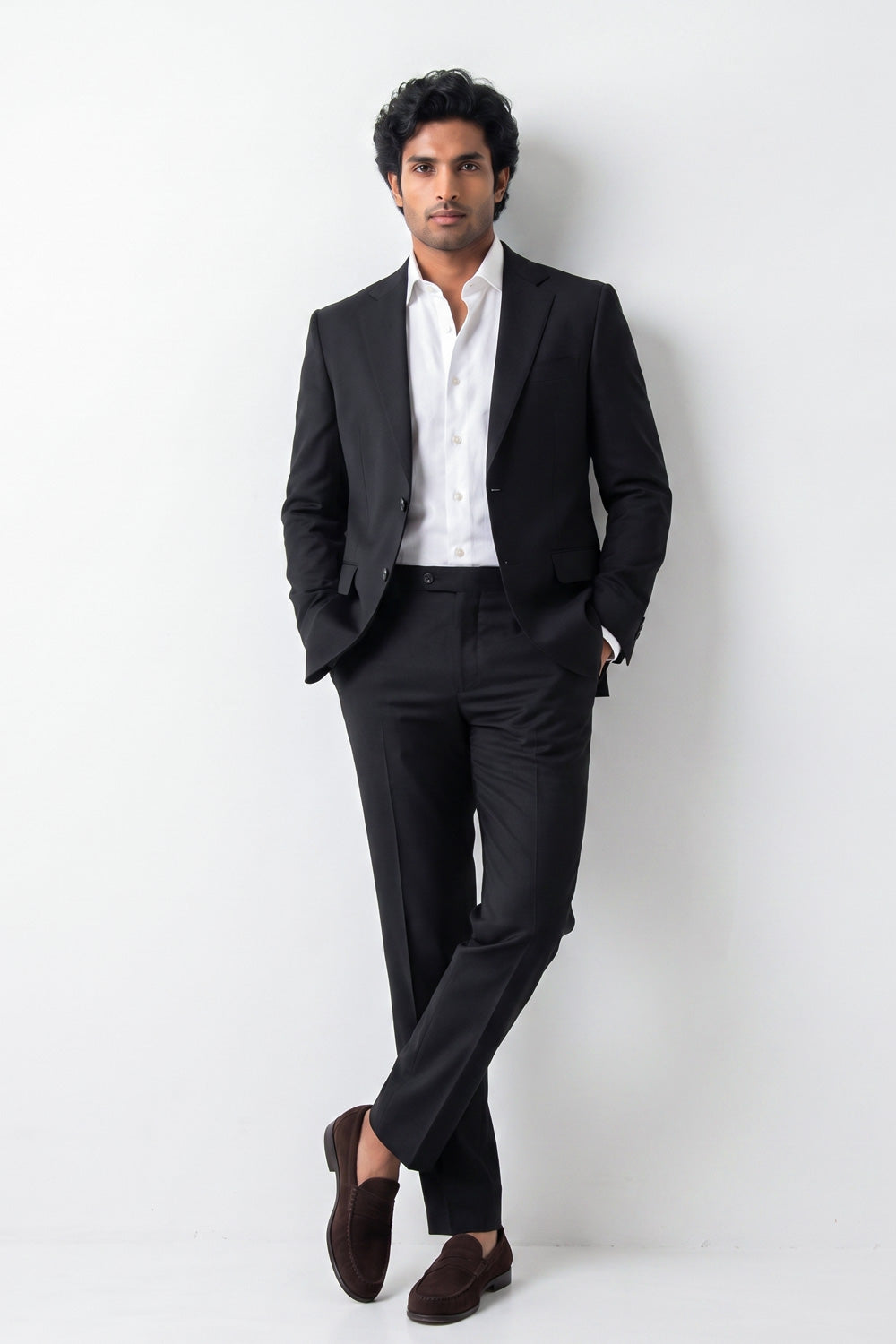 A man wearing a black two-piece hemp suit with a white dress shirt and dark brown loafers, standing against a plain white studio background.