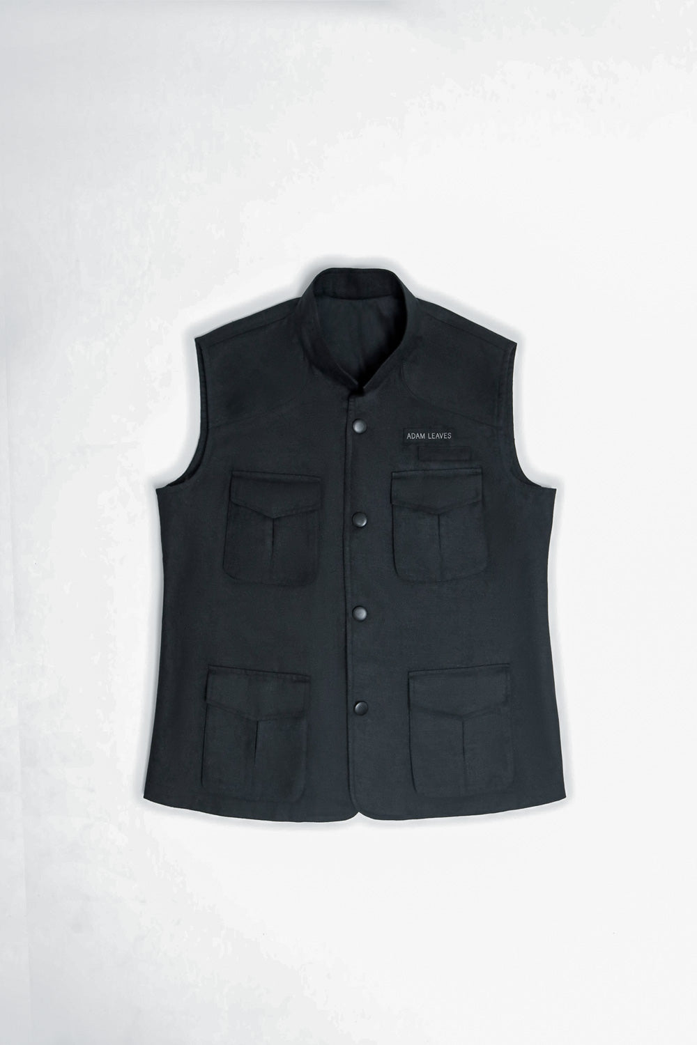 A black sleeveless button-front vest with a stand collar, laid flat on a light gray background. It features four front flap pockets and a small white embroidered logo on the upper right chest.